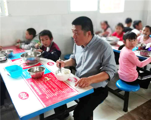 图为永胜学校主持工作的副校长敖文生与学生共同就餐.jpg 图为永胜学校主持工作的副校长敖文生与学生共同就餐.jpg