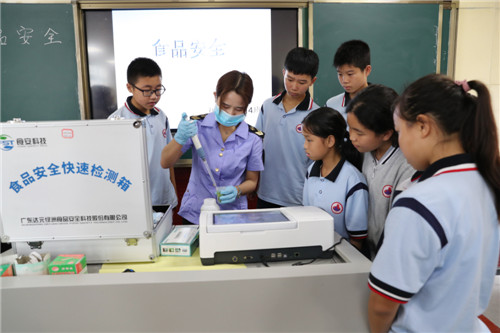 6月24日，广安市广安区市场管理局工作人员石海霞正在广安中学实验室向学生演示用快检设备检查蔬菜是否有农药残留。_副本.jpg
