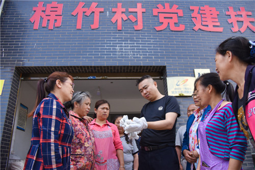 在四川省泸州市叙永县向林镇绵竹村的劳保手套加工党建扶贫车间，泸州市公安局派驻第一书记周亚正在了解手套生产情况_副本.jpg